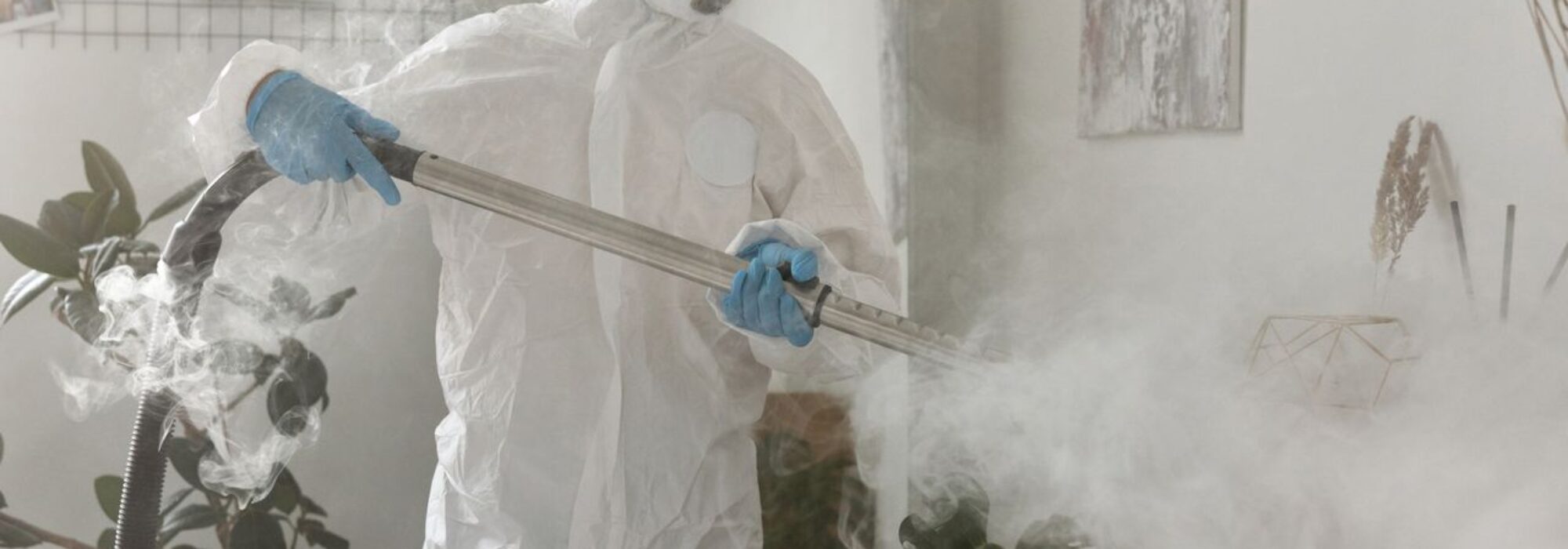 Person in PPE fumigating indoors for health safety during COVID-19.